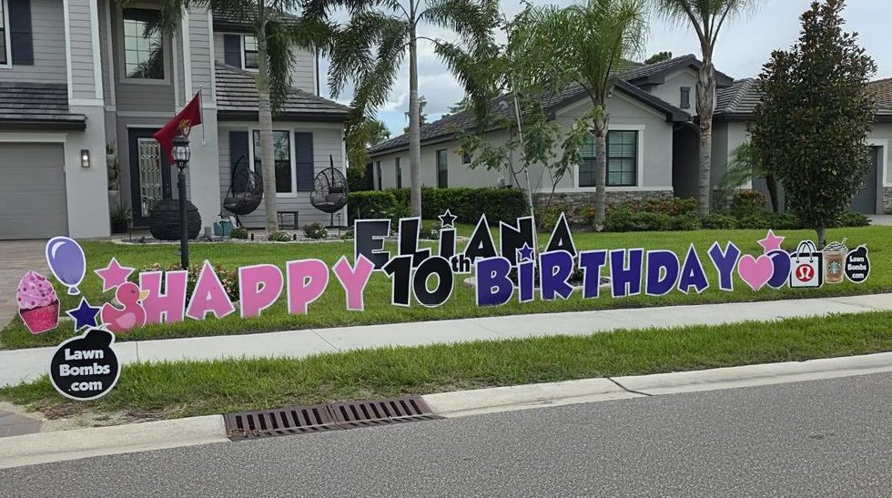 A real LawnBombs sign: pink, black and purple letters spelling Eliana Happy 10th Birthday across a front lawn, with cupcake, balloon, star and heart cutouts